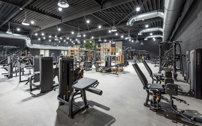 Commercial gym facility showing complete weight training equipment including barbells dumbbells and machines for comprehensive strength training programs - gym training environment InfoProds 2026
