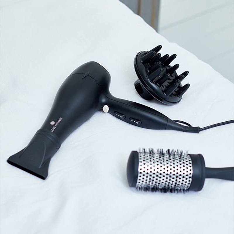 Woman blow drying hair with proper technique using heat protection for safe styling