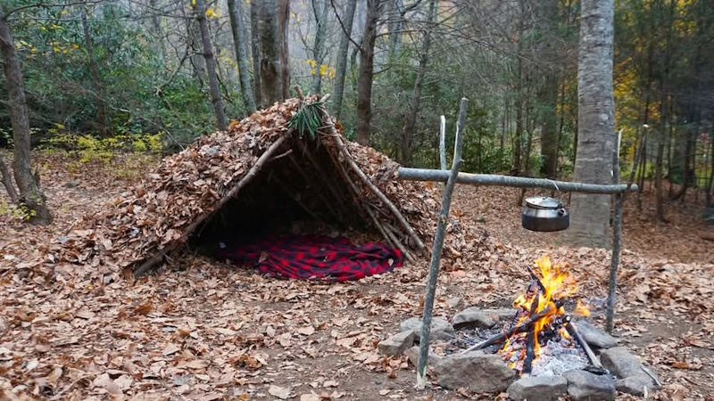 Wilderness emergency shelter debris hut construction showing proper insulation layers protecting against hypothermia during first 24 hours lost survival - InfoProds 2026