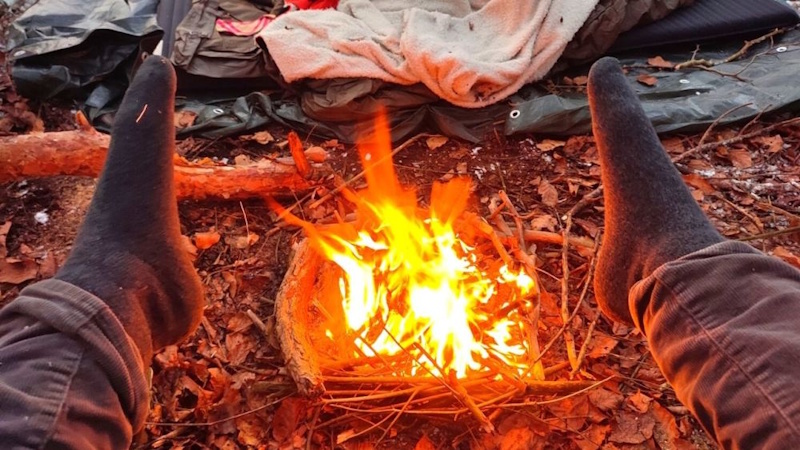 Wilderness emergency fire building showing proper tinder preparation and ignition techniques providing warmth and rescue signal visibility - InfoProds 2026