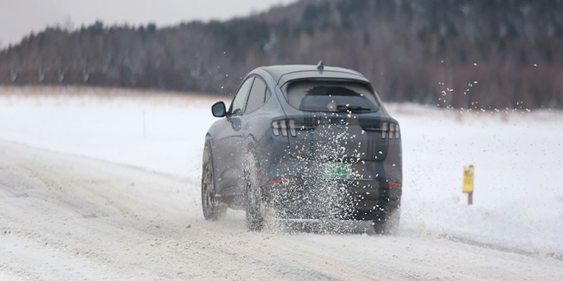 Electric sedan navigating snowy winter conditions demonstrating cold weather performance testing for range efficiency and traction capabilities in sub-zero temperatures - winter EV performance InfoProds 2026
