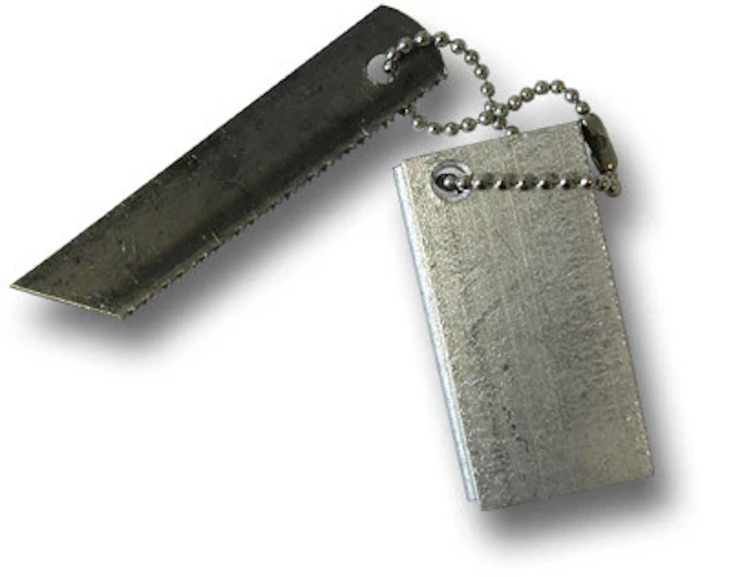 Magnesium fire starter block with attached ferro rod and metal scraper tool on outdoor survival backdrop demonstrating technique dependent fire starting method requiring practice for reliable wet weather emergency ignition capability wilderness preparedness equipment InfoProds 2026